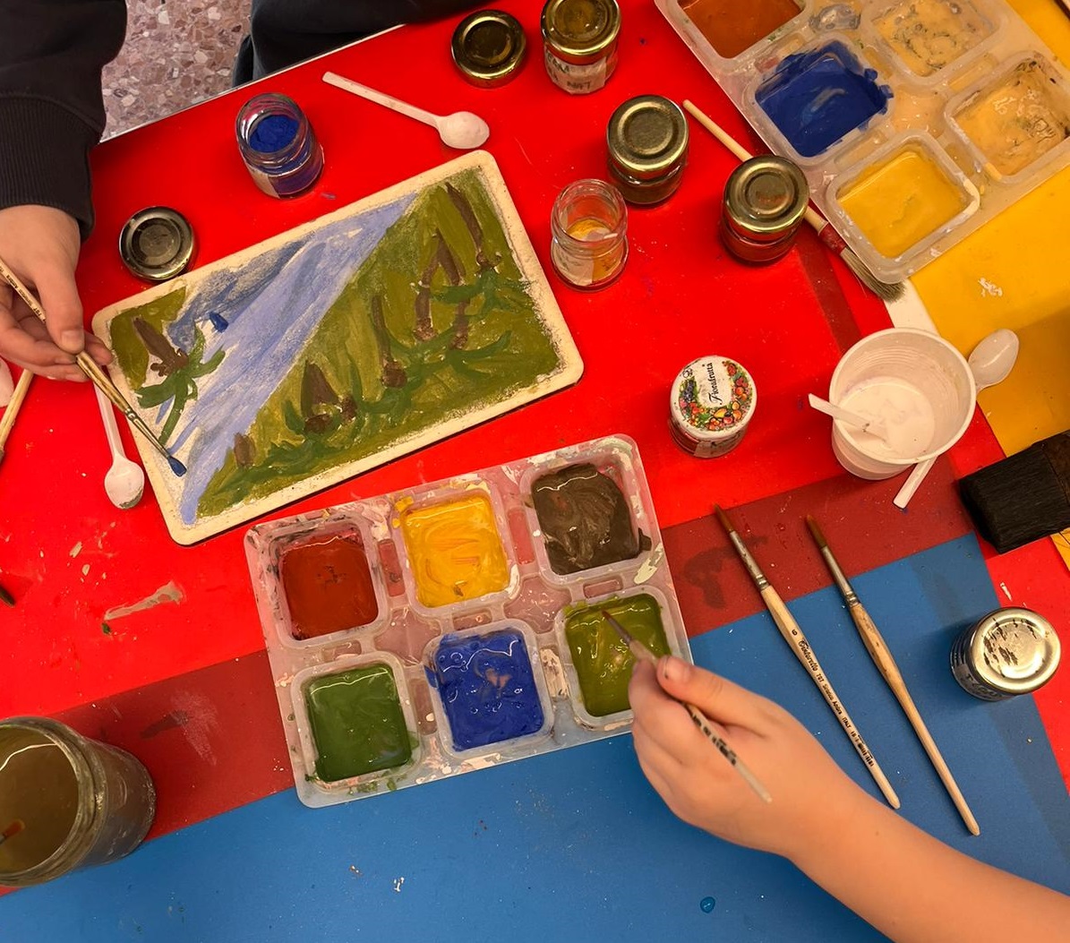 Immagine illustrativa attività - mani di bambino che usano acquerelli